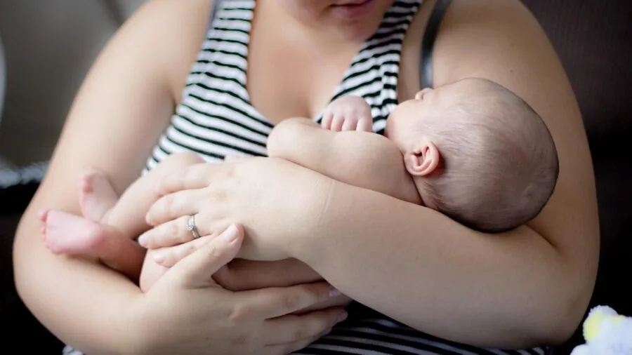 Parent checking baby monitor device while baby sleeps peacefully in nursery room